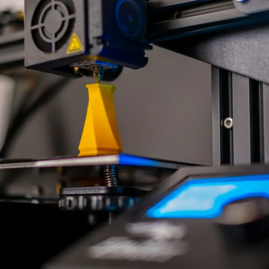 3D-Drucker, der eine gelbe Vase auf einer Druckplattform erstellt.