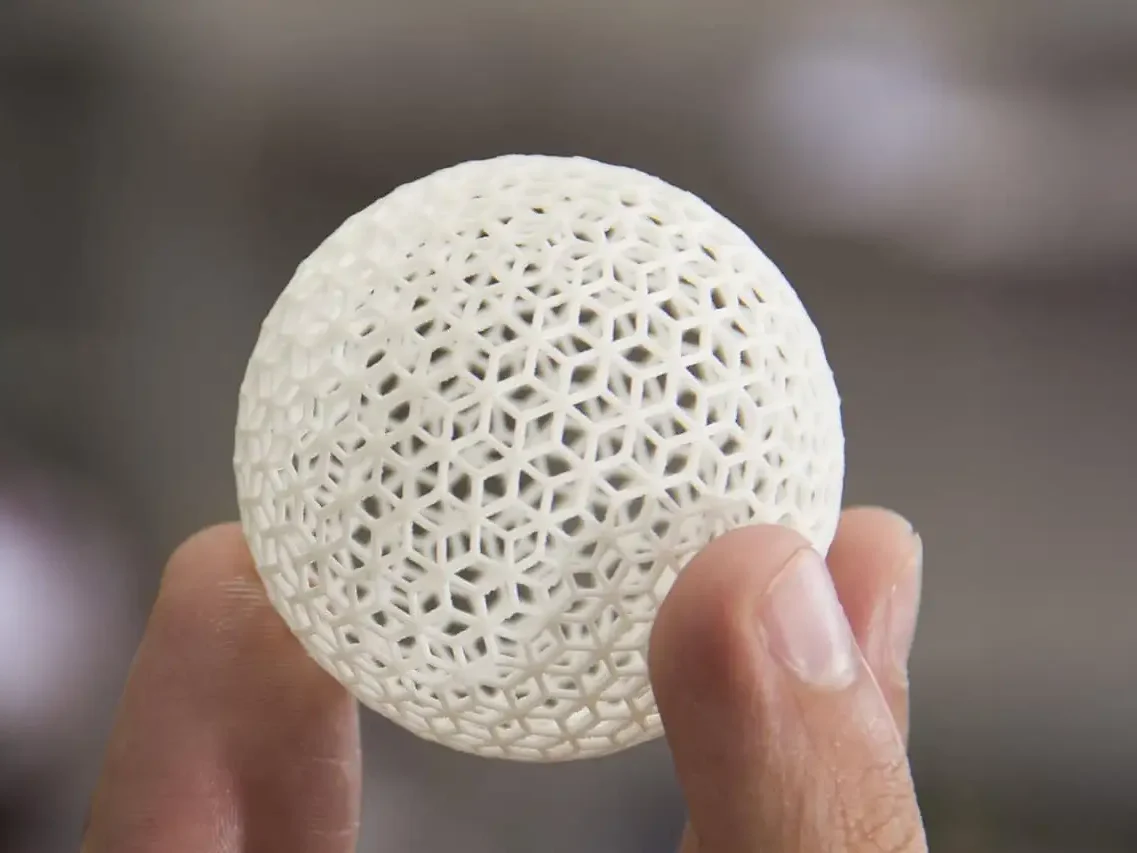 Eine handgehaltene, luftige, kugelförmige 3D-Struktur mit vielen kleinen Öffnungen.