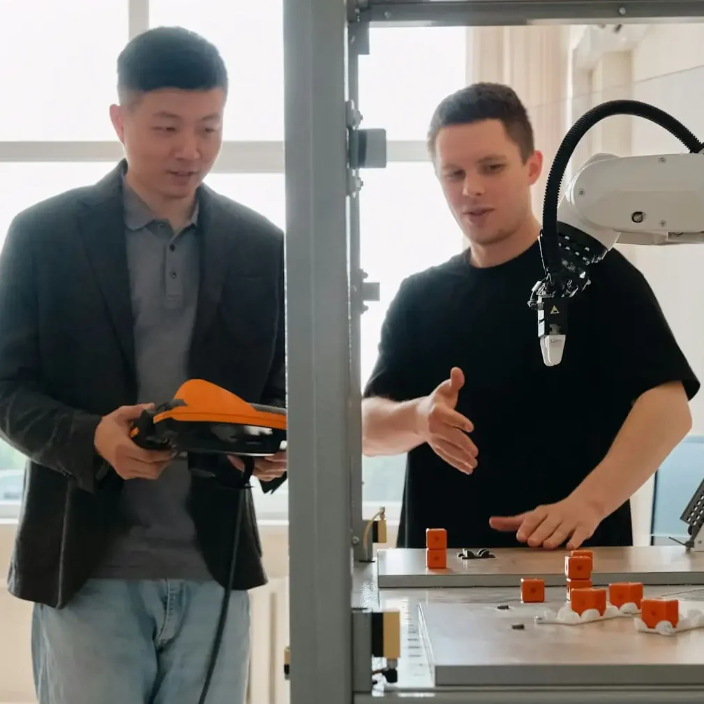 Zwei Männer beobachten einen 3D-Drucker und diskutieren darüber.