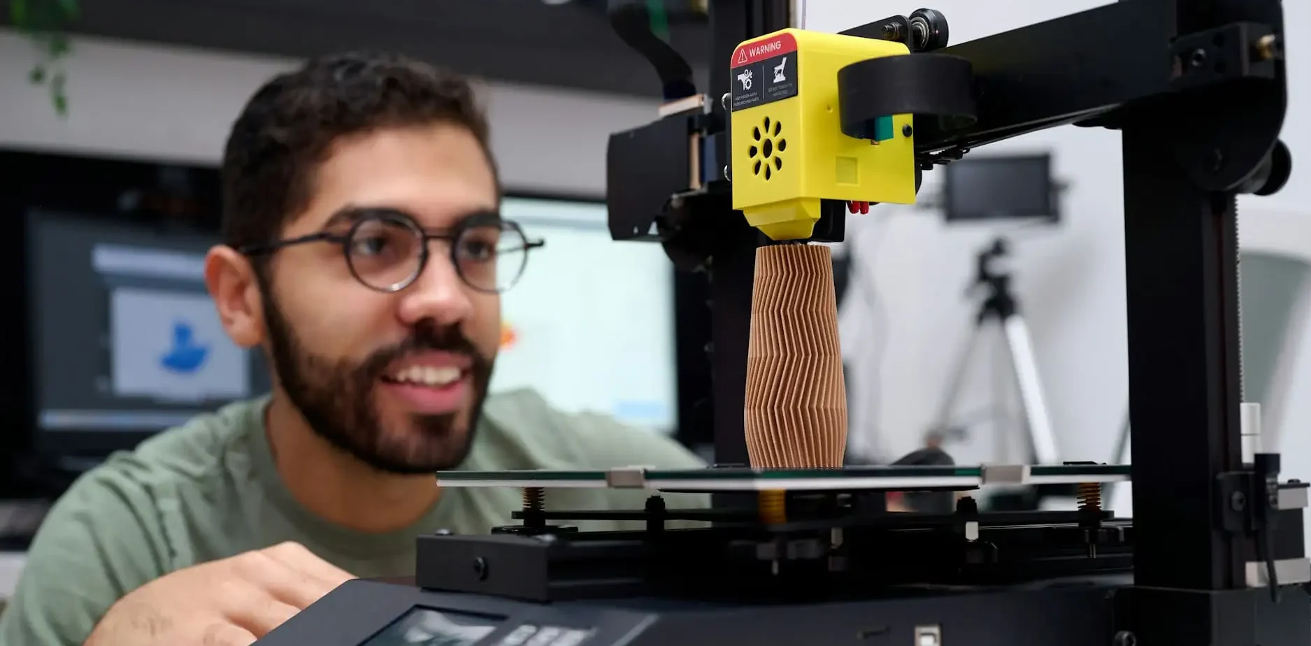 Mann beobachtet einen 3D-Drucker mit einem gedruckten Objekt.