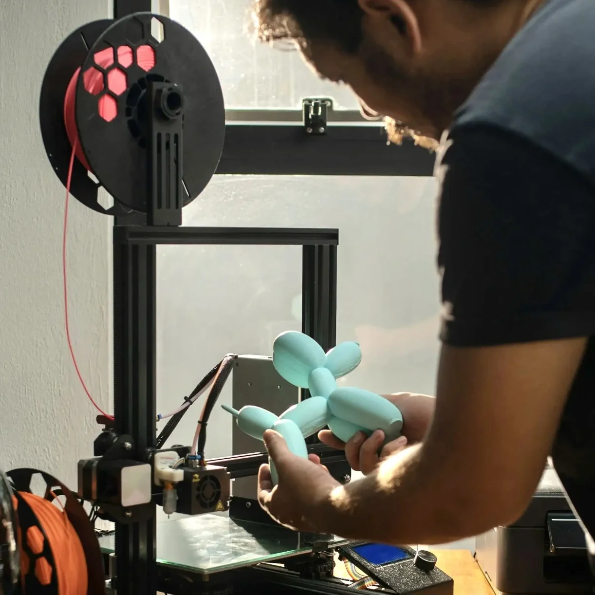 Eine Person hält eine orangefarbene geometrische 3D-Figur in den Händen.